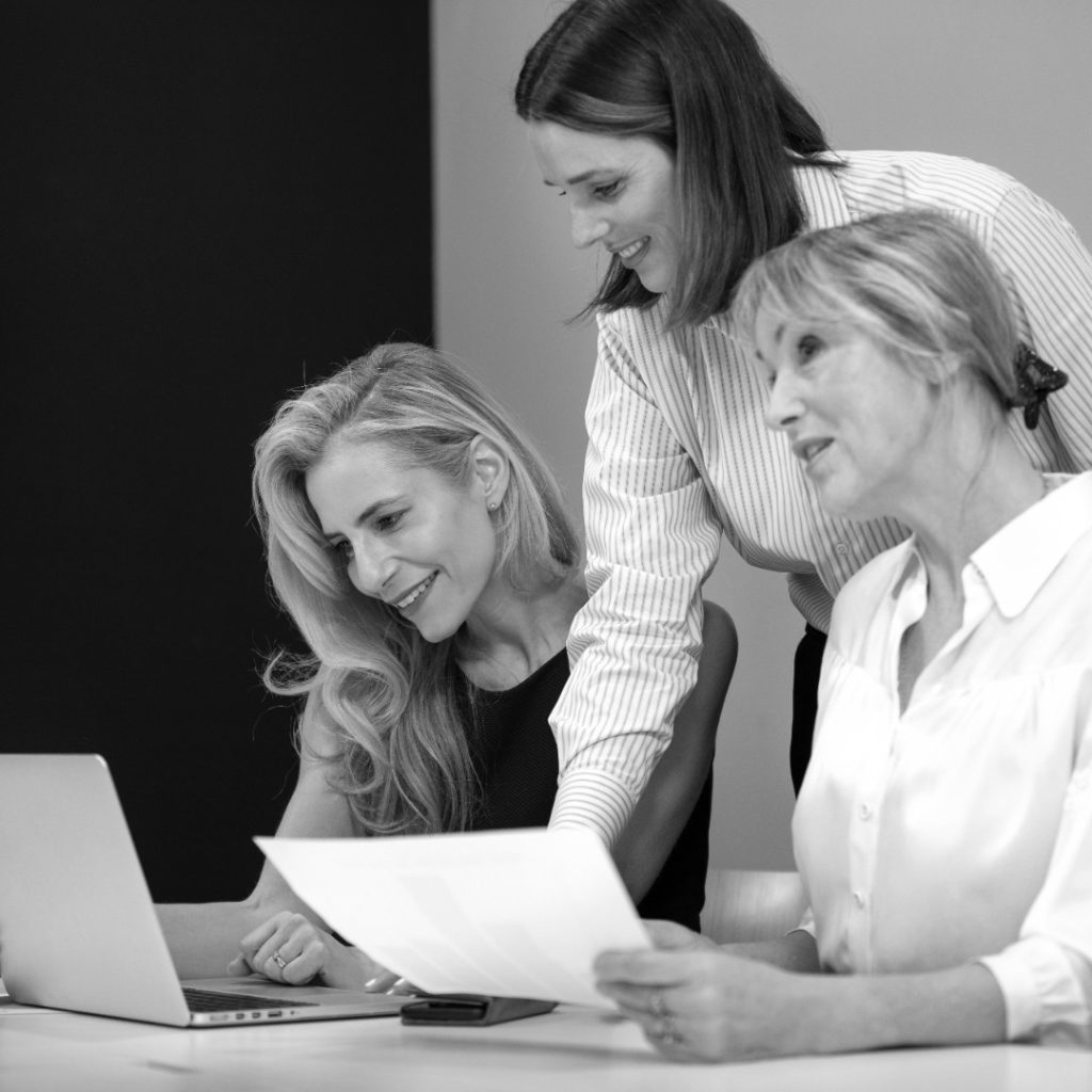 mujeres sonrientes de tiro medio que trabajan con una computadora portatil photoaidcom greyscale 1080x1080