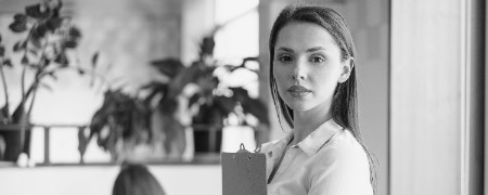 retrato de un atractivo joven mujer de negocios tenencia portapapeles en oficina photoaidcom greyscale 450x180
