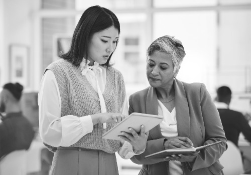 internship tablet woman with mentor discussion with notebook news business info advice office teamwork leader asian worker talking learning data analytics digital agency photoaidcom greyscale 500x350