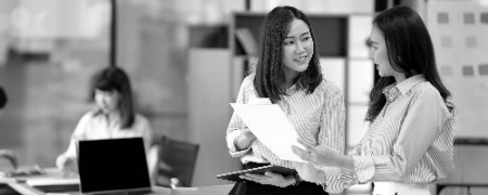 two young businesswoman using digital tablet while standing boardroom two business colleagues having discussion meeting photoaidcom greyscale 450x180
